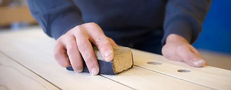 Handwerker beim Schleifen einer Holzoberfläche